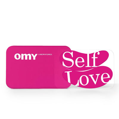 Boîte rose des patchs réutilisables pour les yeux placée à côté des deux patchs sur lesquelles est écrit Self Love.